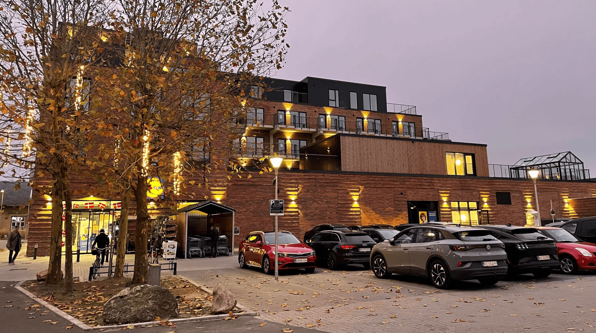 Allerød Downtown facade i aftenslys med butikker, boliger og skiltning fra Skomø