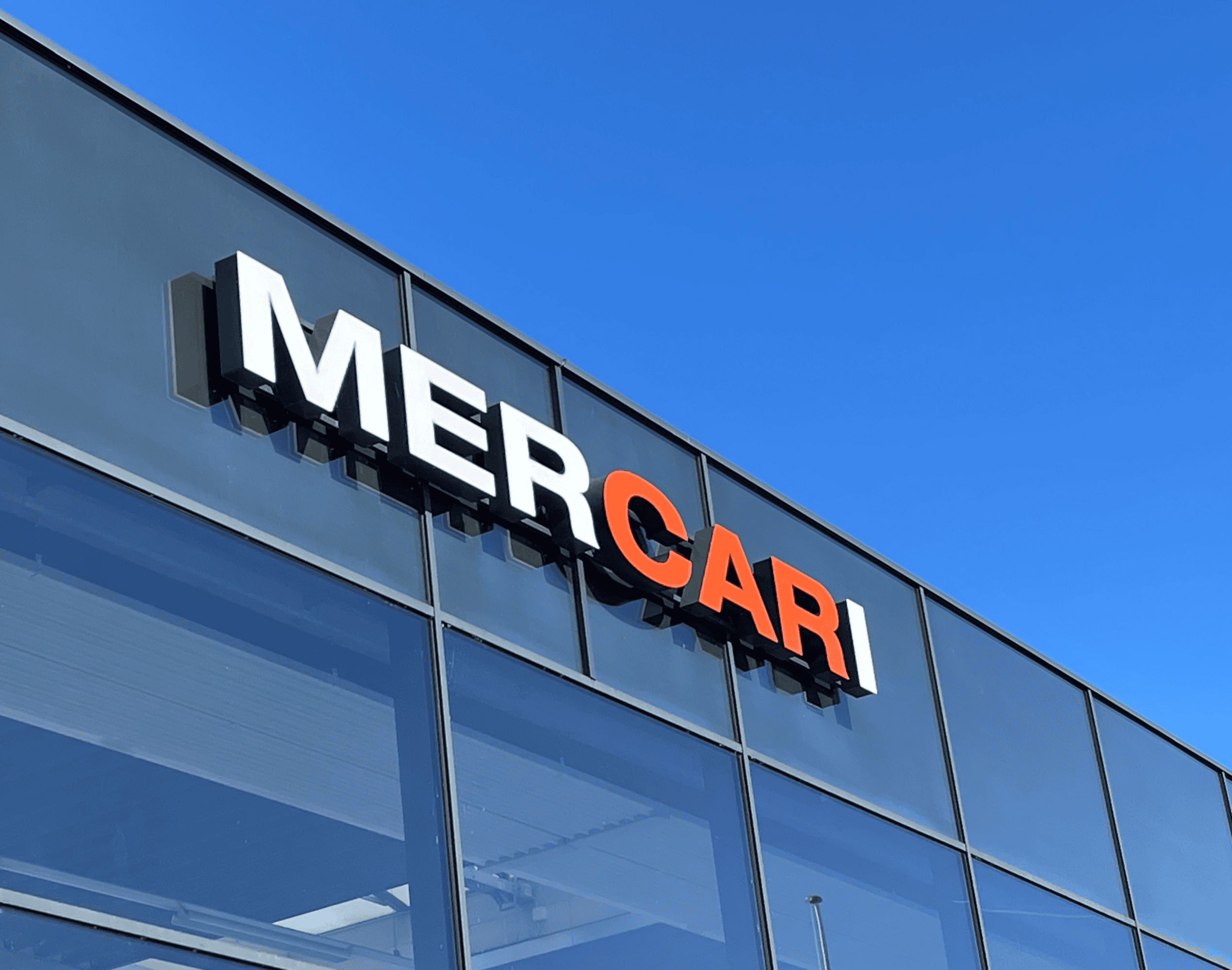 Facadeskilt med udskårne bogstaver fra Skomø monteret på moderne glasfacade med MERCARI logo.